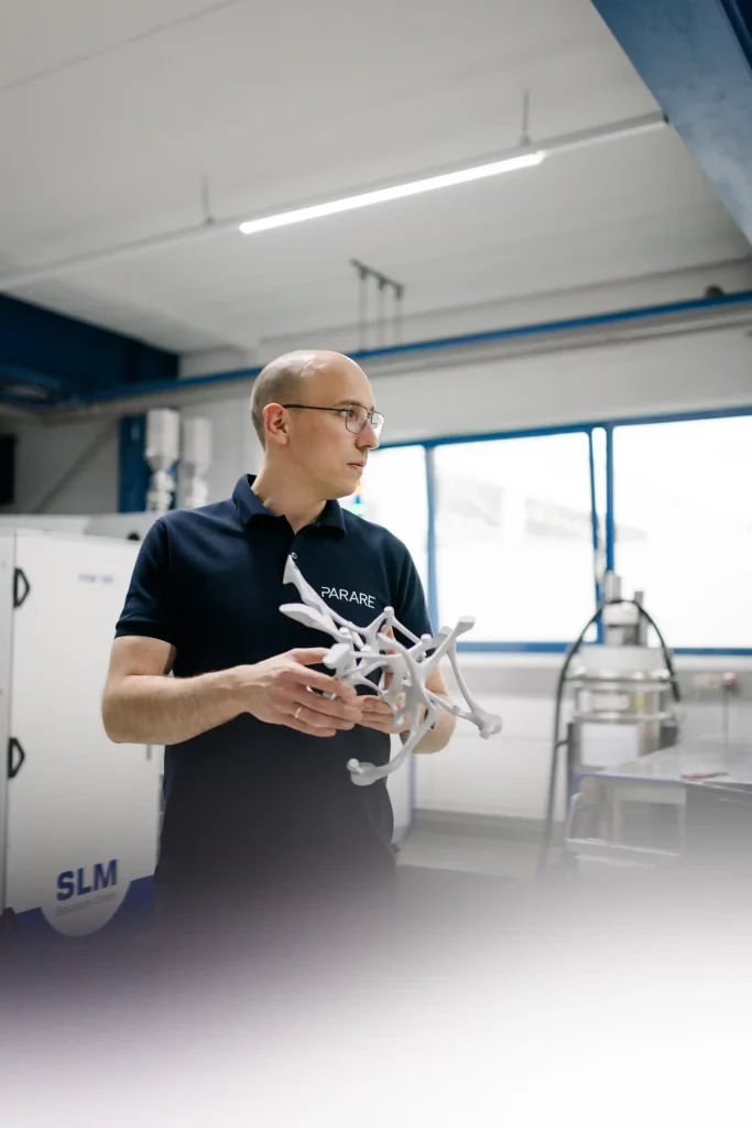 Ingenieur im Produktionsumfeld hält komplexes 3D-gedrucktes Metallbauteil