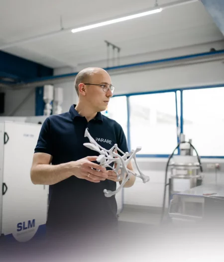 Ingenieur im Produktionsumfeld hält komplexes 3D-gedrucktes Metallbauteil